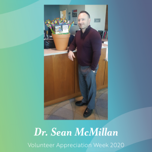 photo of volunteer Sean McMillan standing next to potted pinwheel garden