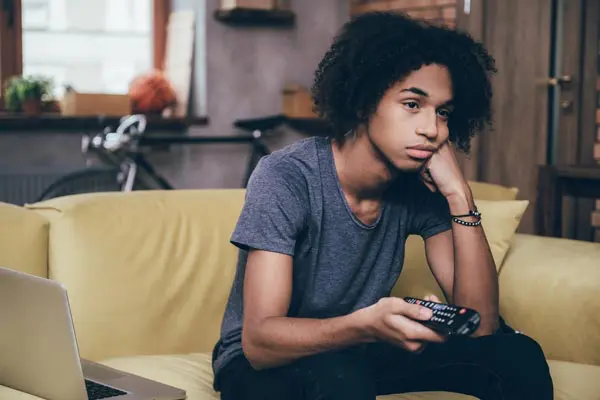 adolescent boy sitting on couch watching TV