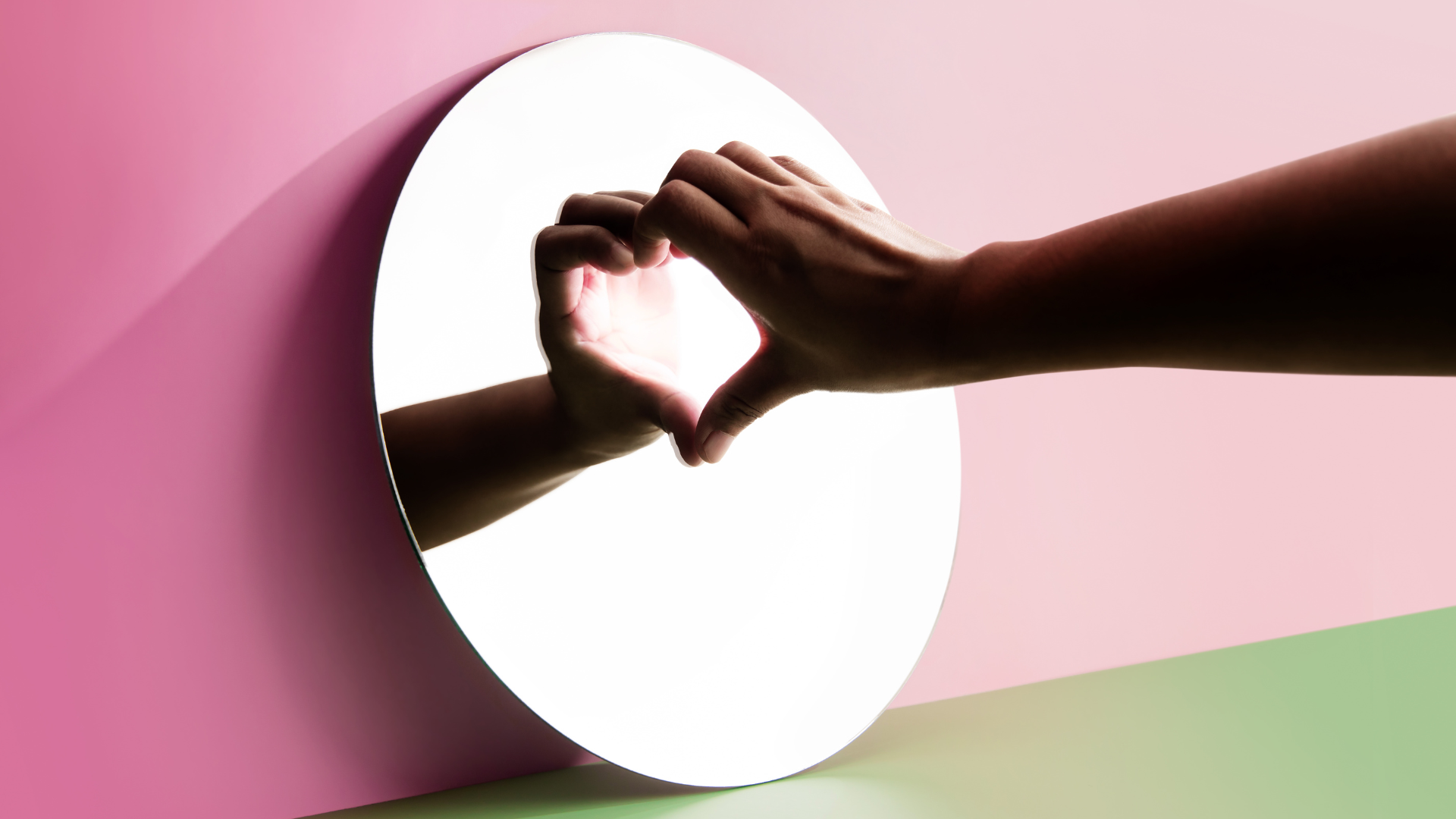 person touching a mirror making a heart with the reflection, representing the self-love challenge