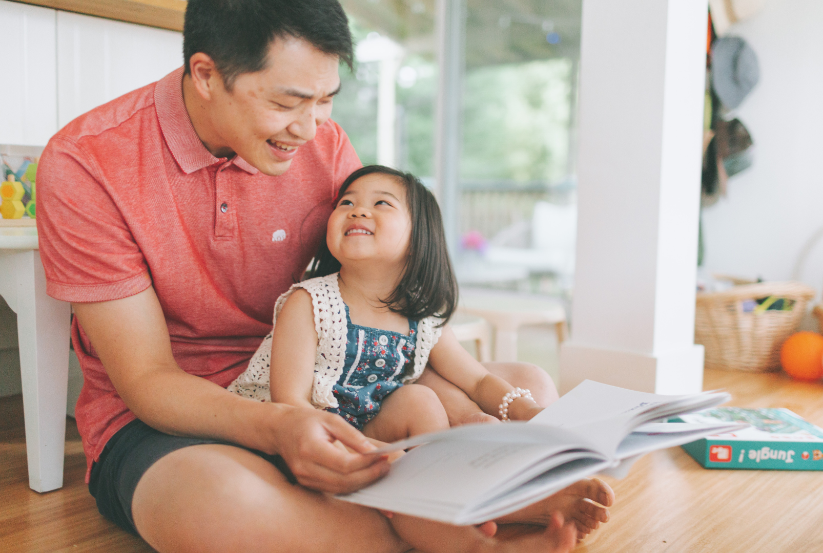 A father and his young daughter are reading together.