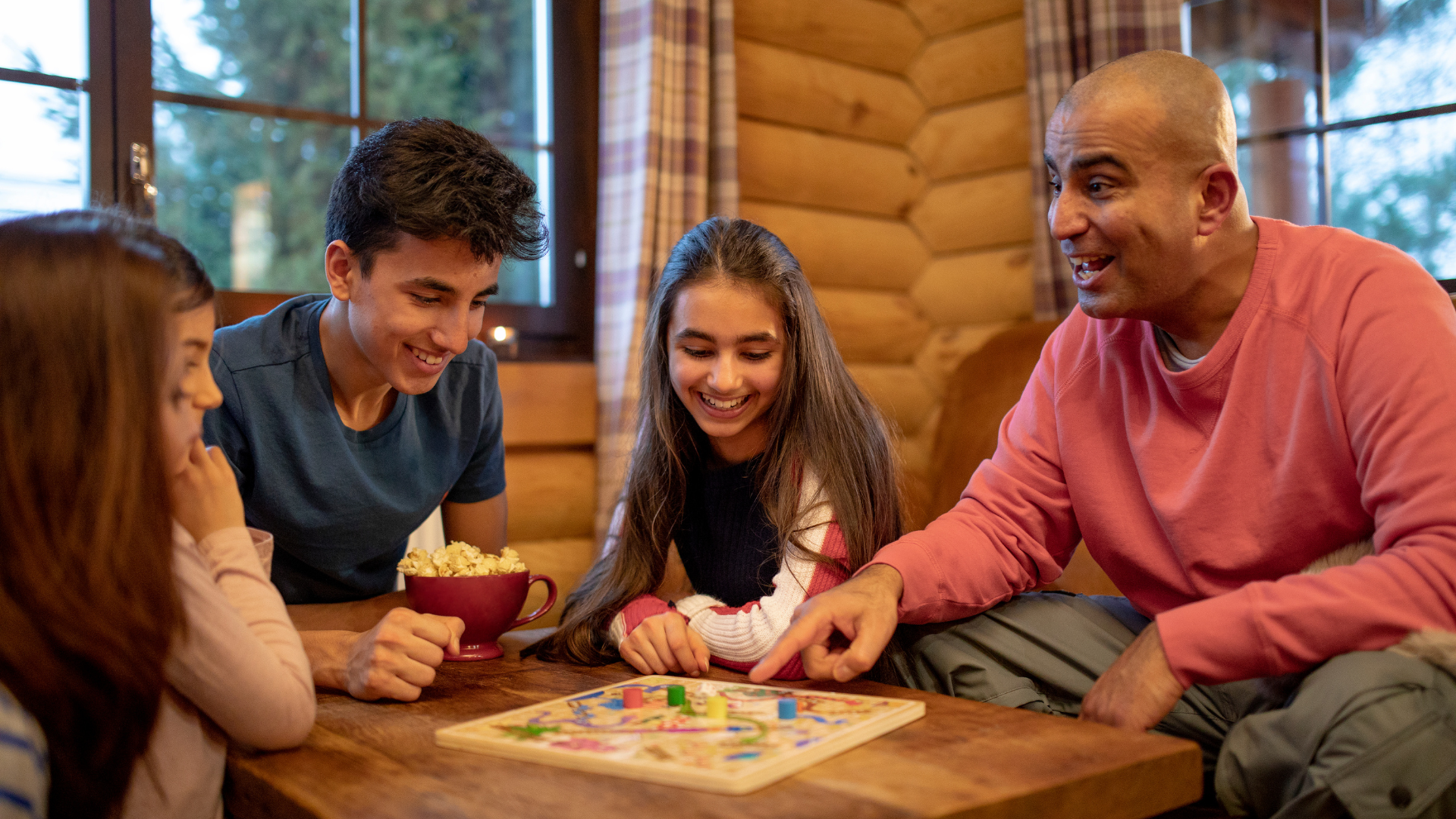 A family laughs and has fun while playing a board game together. 
