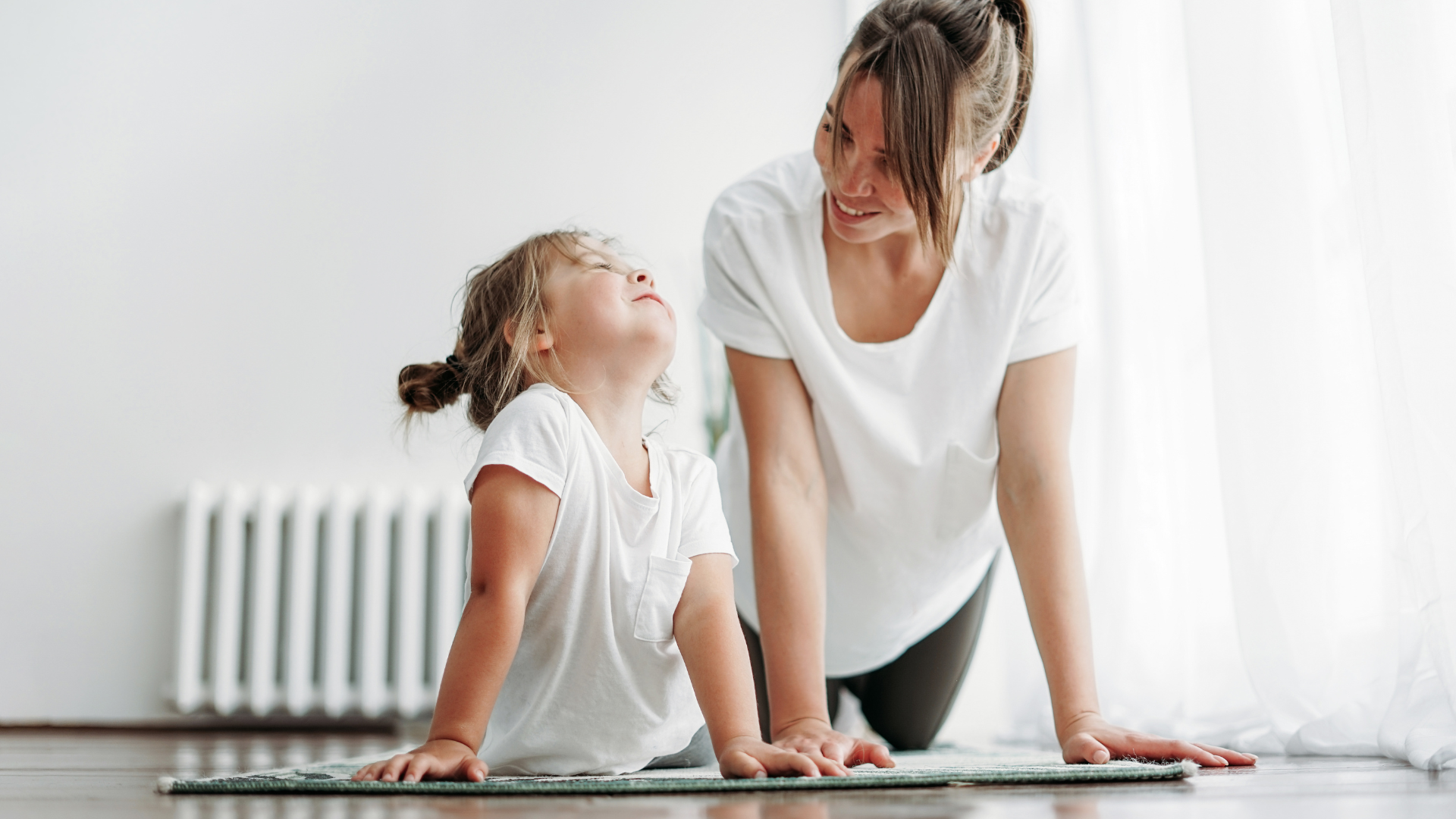 This mother and daughter practice hygge by doing yoga and spending quality time together. 