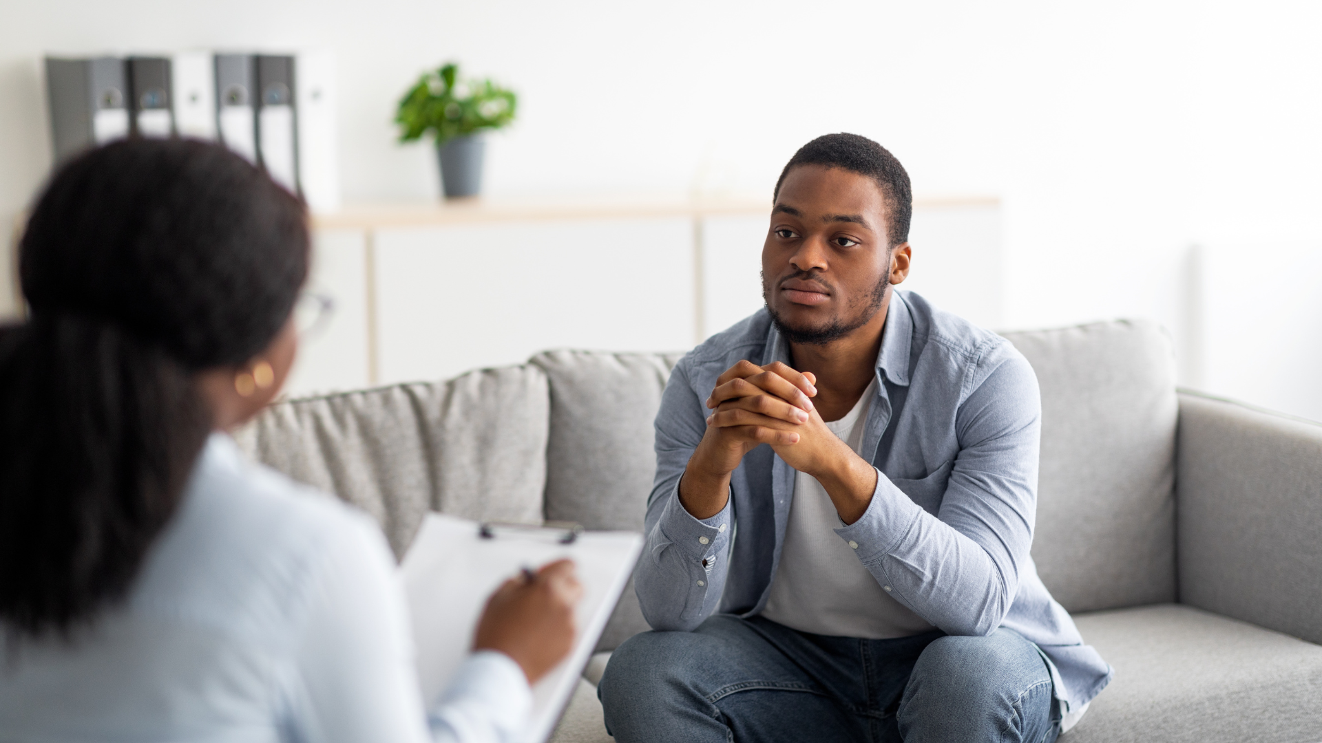 A young Black man has sought out support from a mental health professional. 