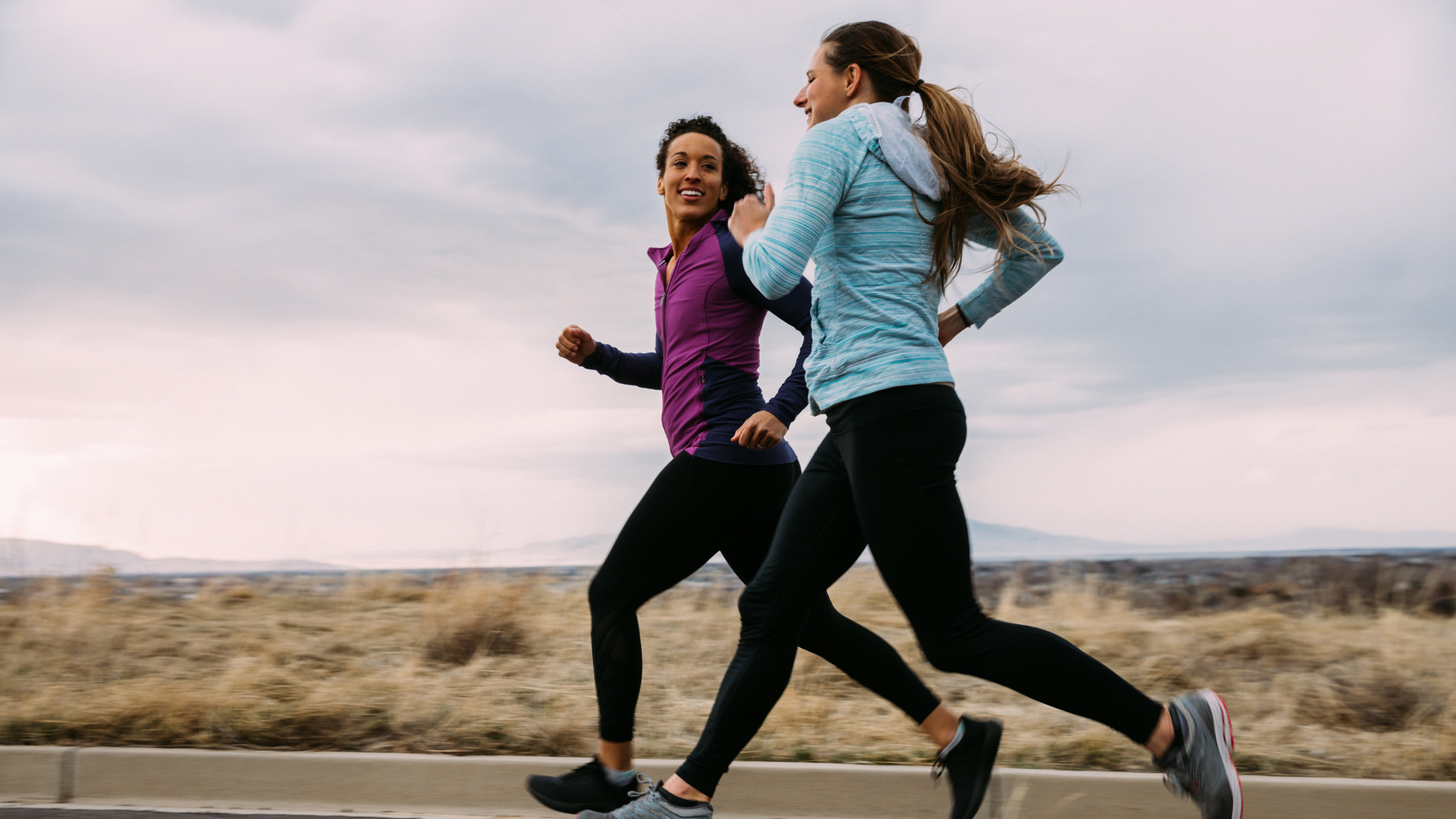 Two women are outside running together, benefiting their physical and mental wellness. 