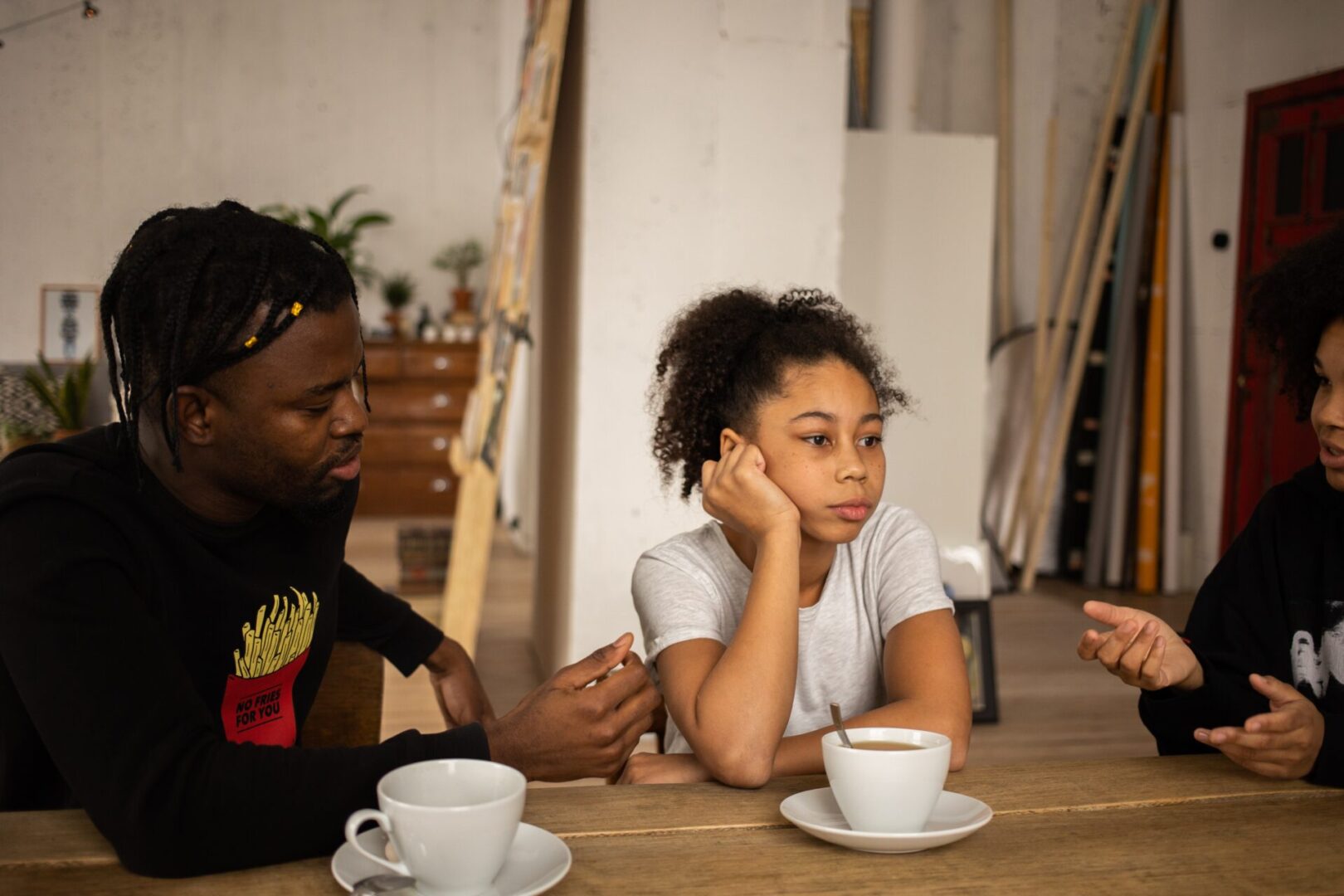 Frustrated black girl between arguing parents at table