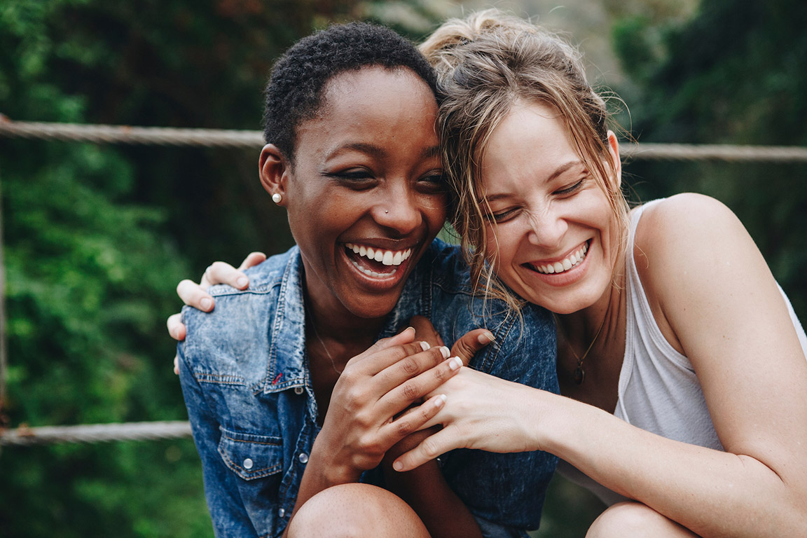 Two female friends laughing and hugging