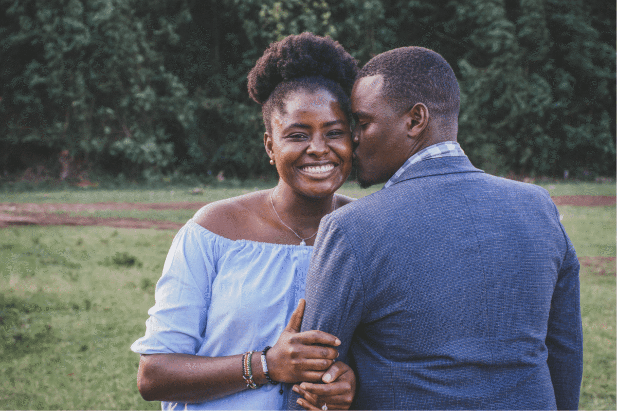 man kissing left cheek of smiling happy woman