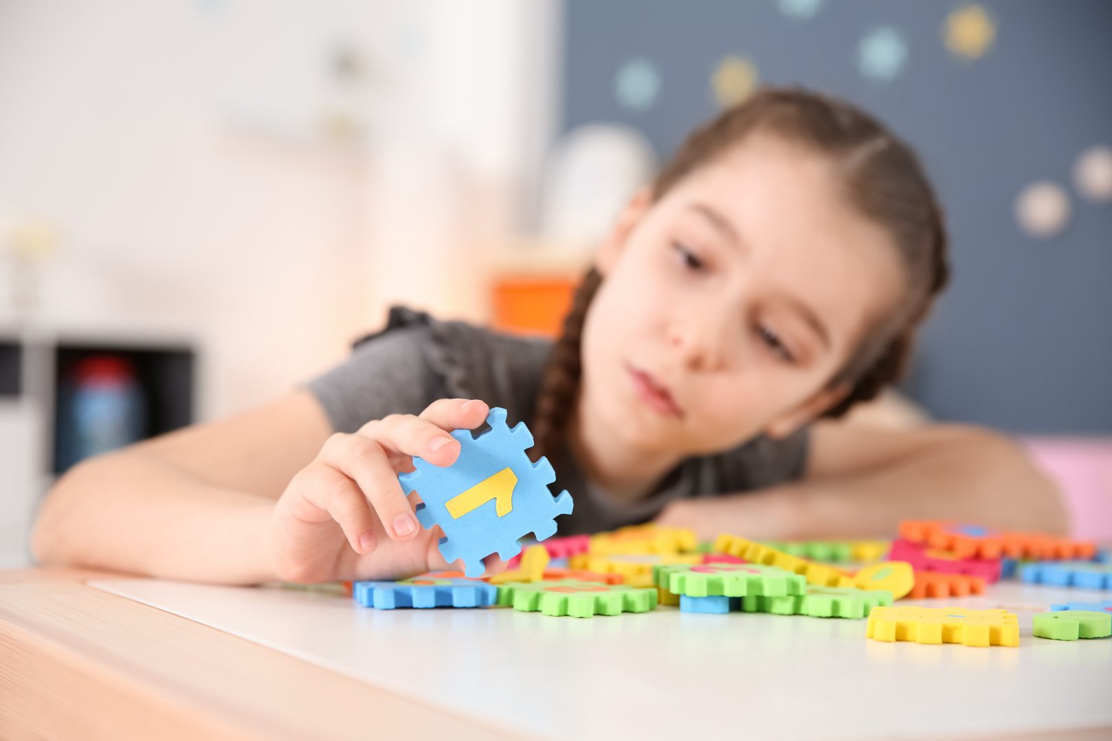Little girl with autism disorder playing at home, closeup of puzzles