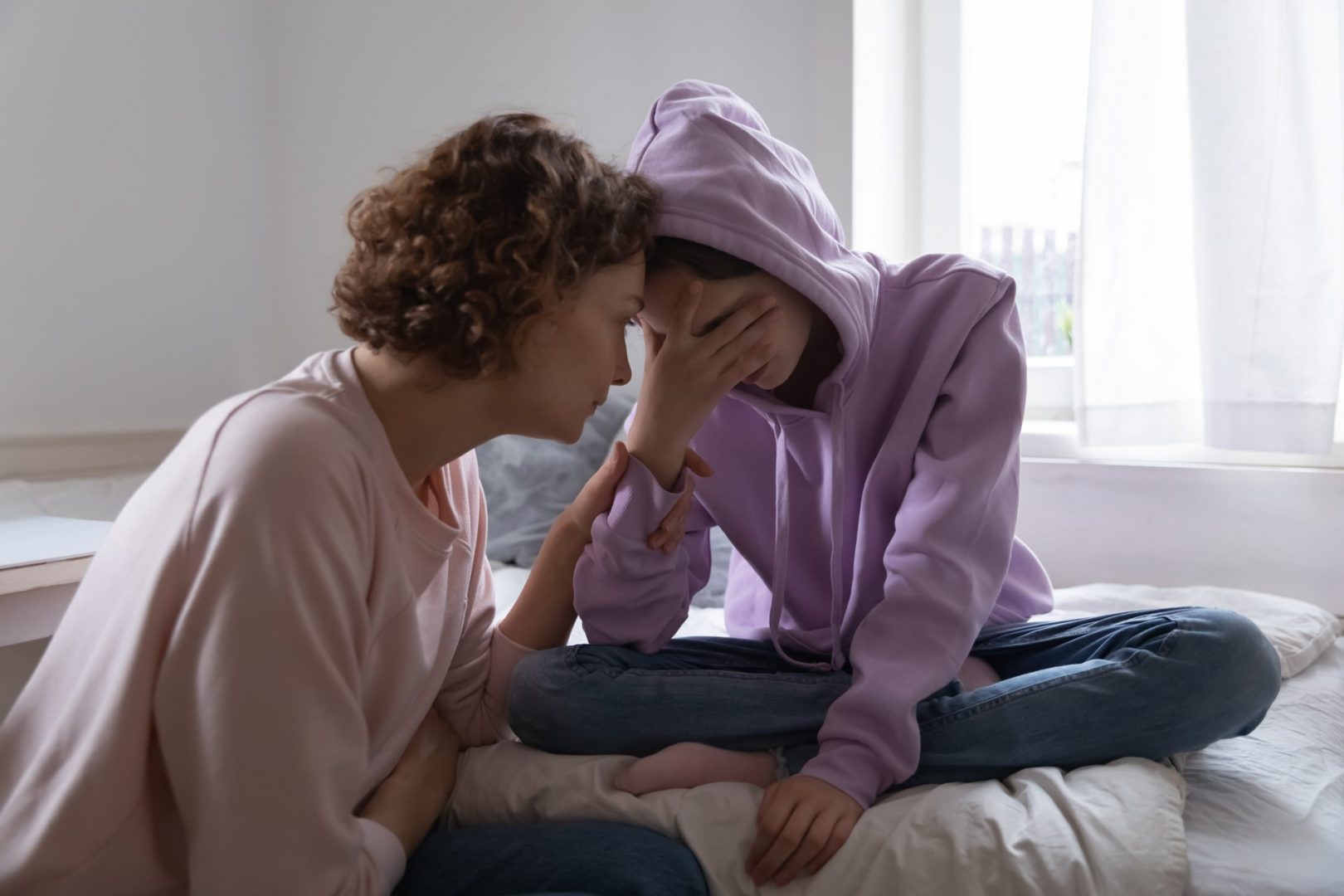 Depressed teenager being comforted by mother