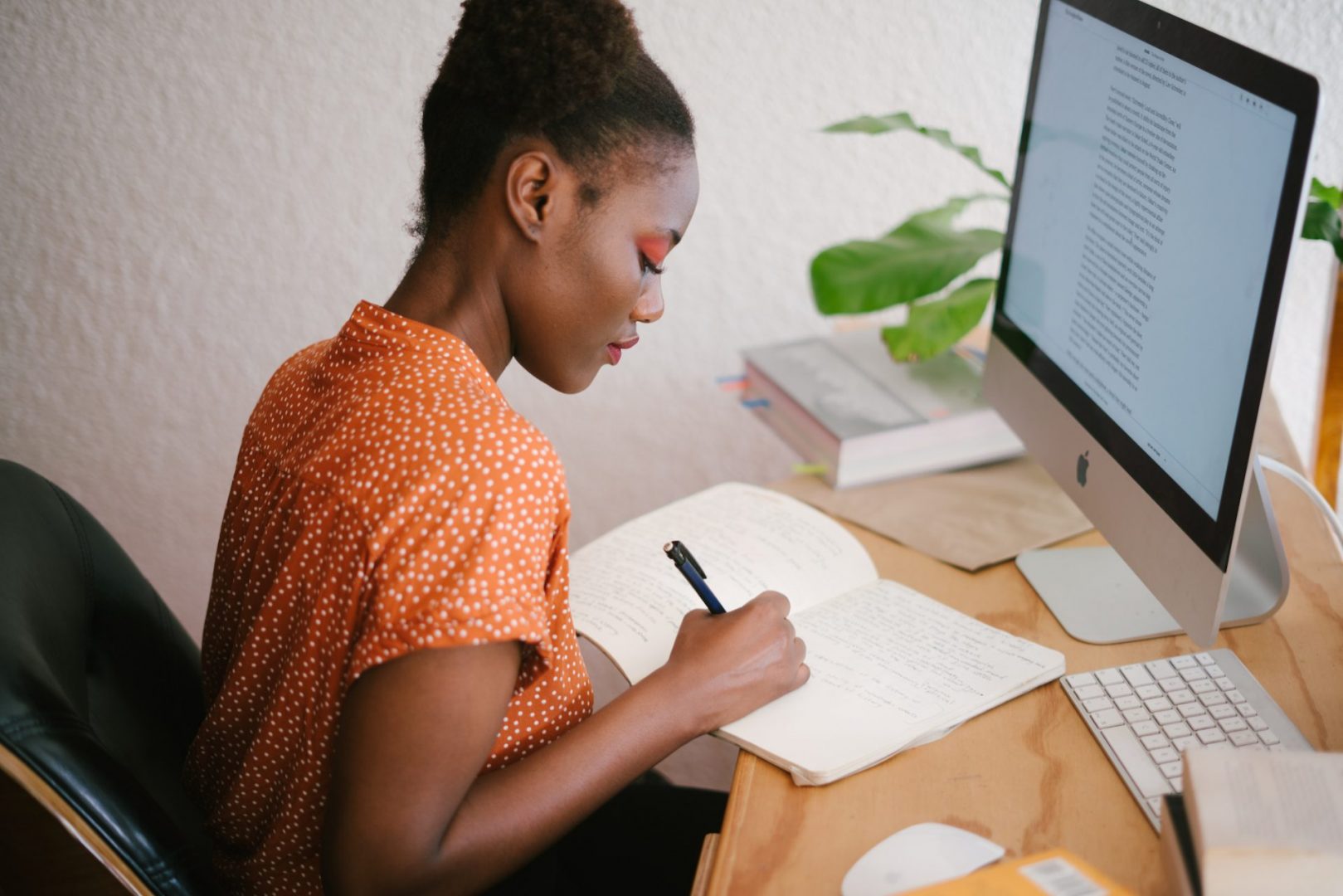 intern working at her desk and writing in a notebook