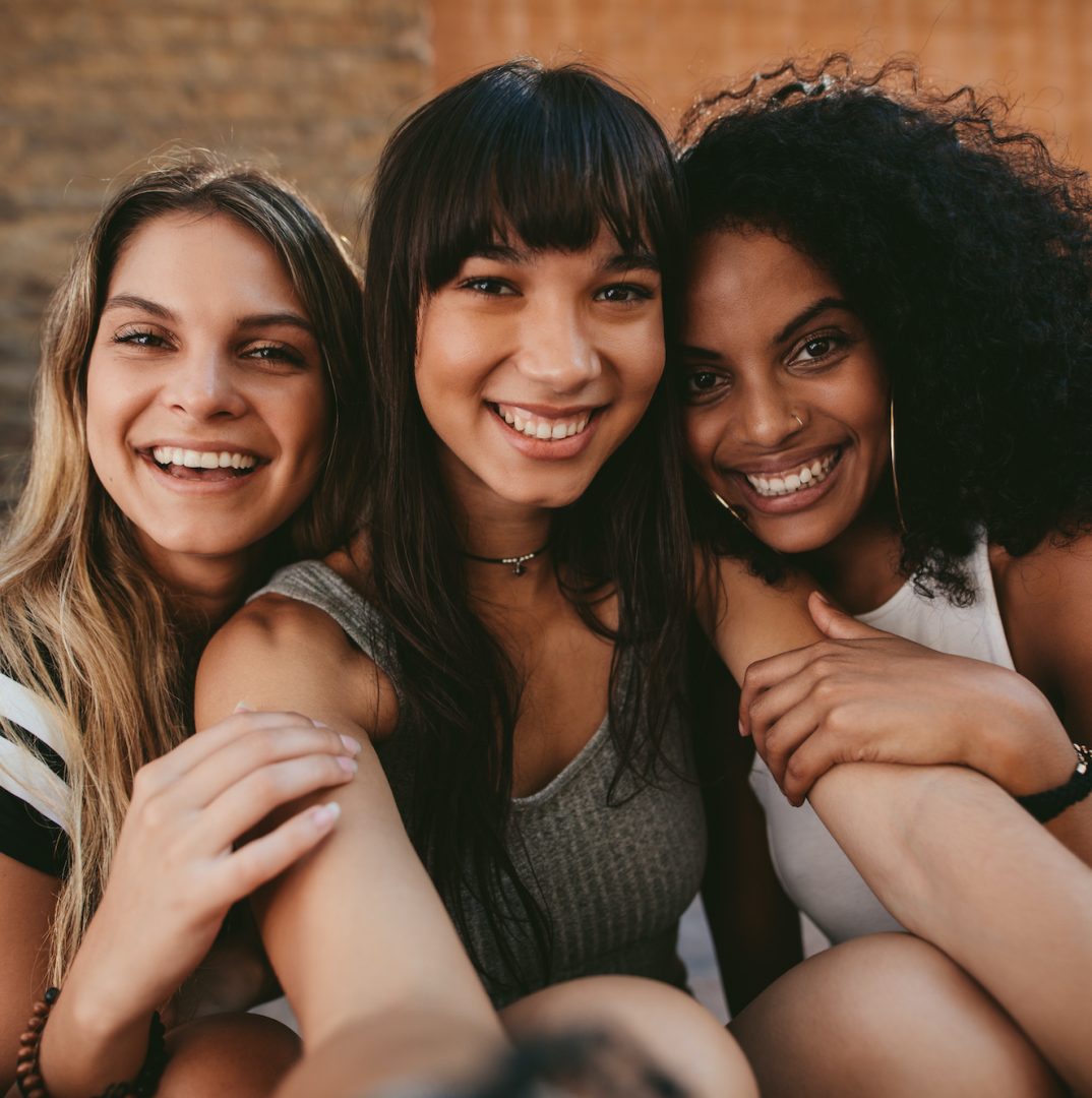 three teen female friends smiling