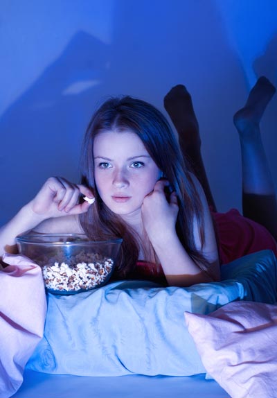 adolescent girl watching TV in dark