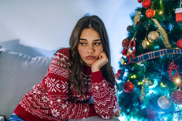 young woman depressed by christmas tree