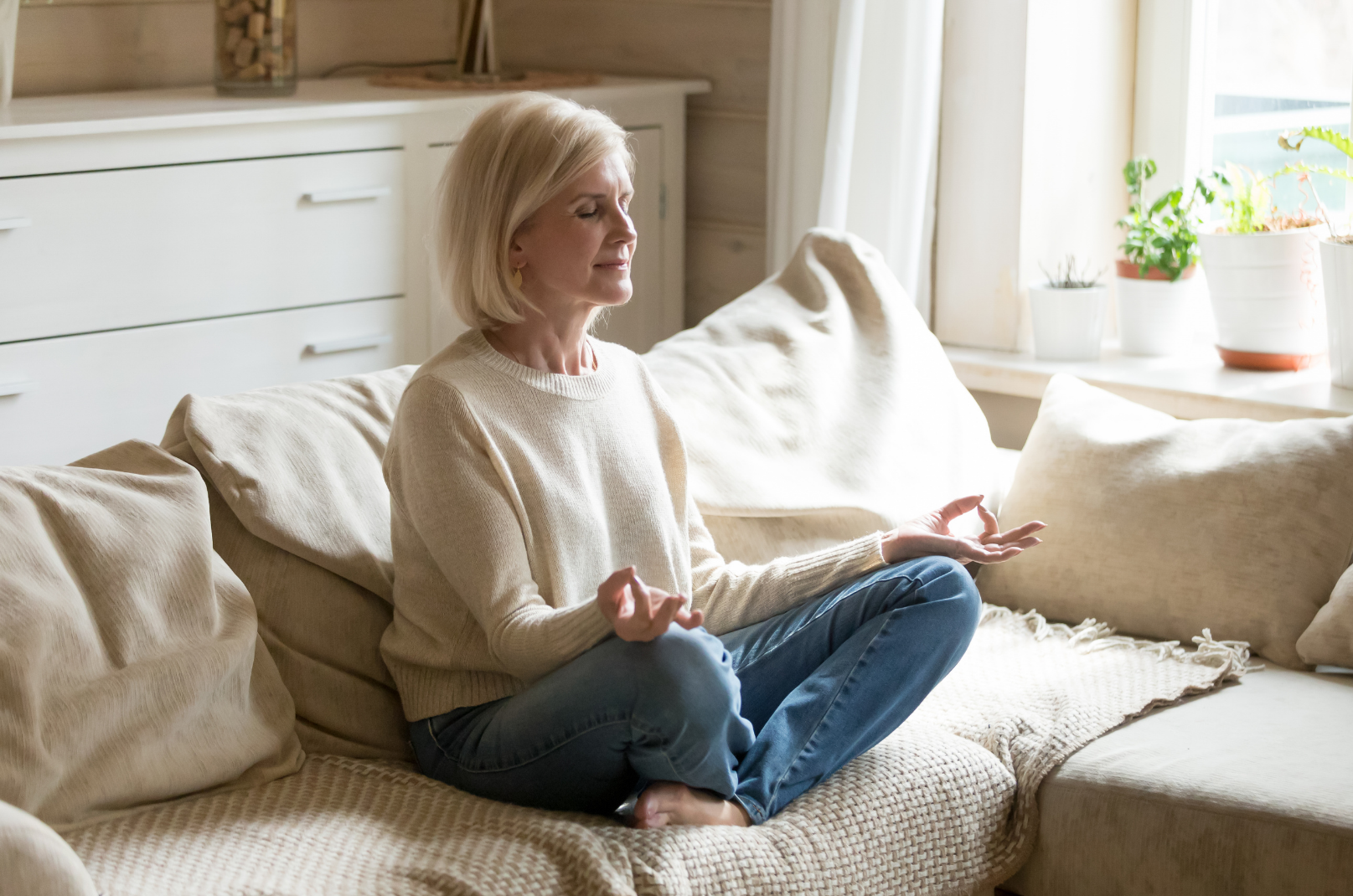 older woman meditating on couch practicing coping skills