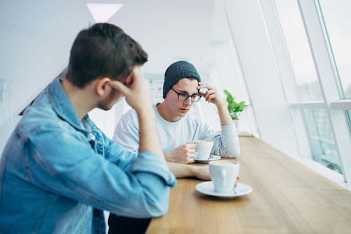 two young men talking over coffee mental health dialogue with a friend