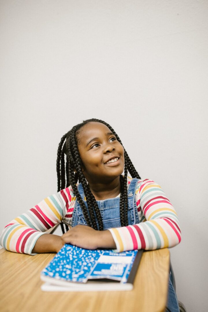 young black girl sitting at school desk and smiling