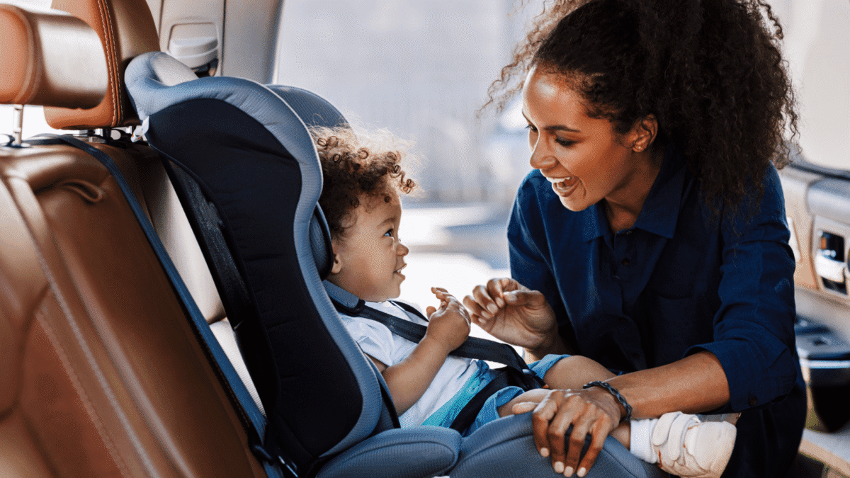 Picture of a woman buckling a baby into a car seat, keeping the baby safe.
