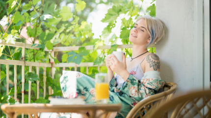 Woman relaxes on her porch in the sunlight, taking her "me time" outside.