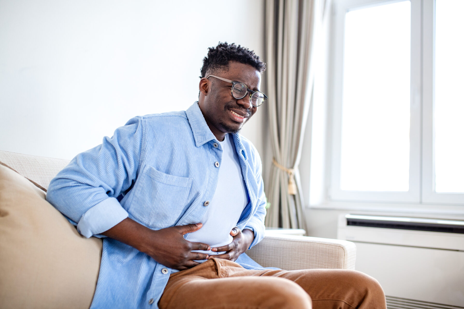 Man holding his stomach, suffering from physical symptoms based on his health anxiety.