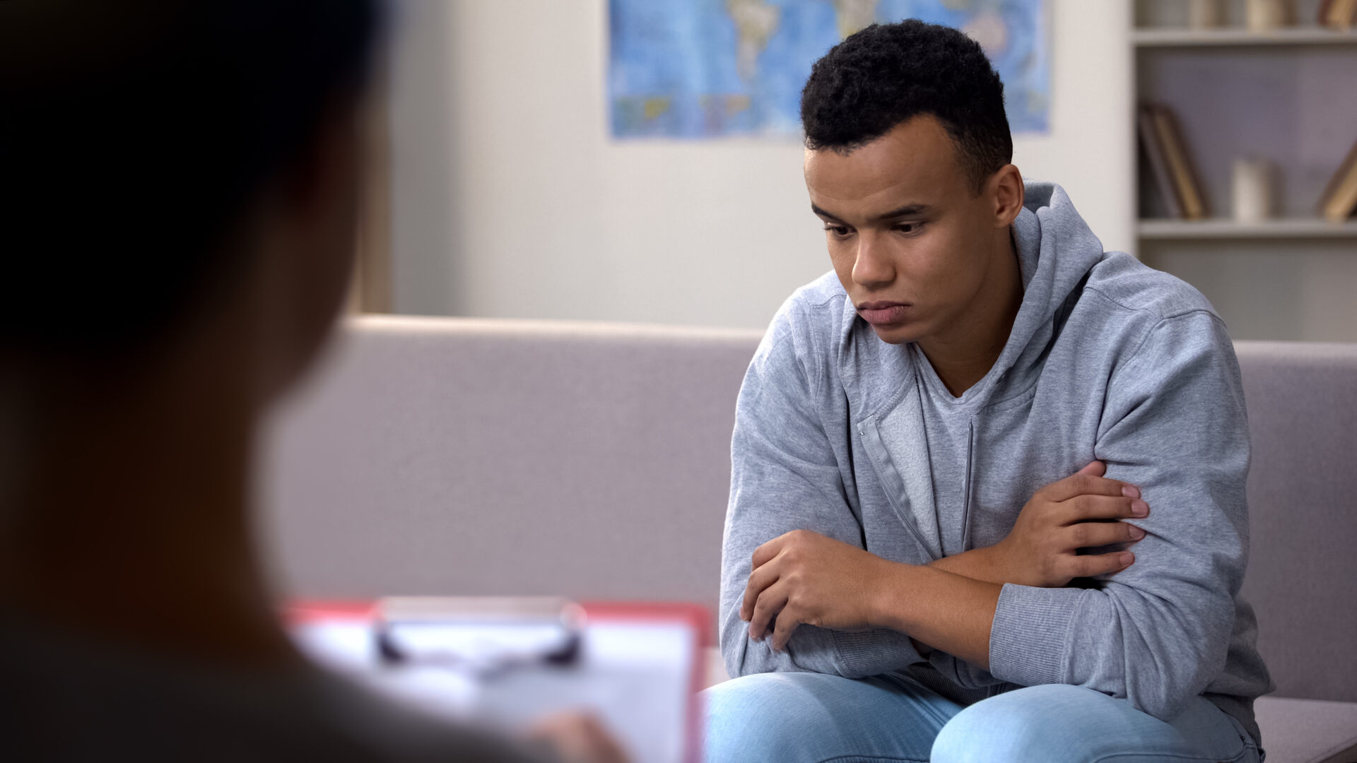 Depressed teenage boy talking to psychologist.