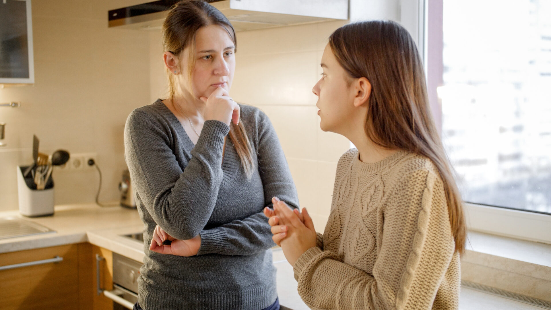 Young mother listening and talking to her teenage daughter complaining about problems and depression. Parent supporting and comforting child.