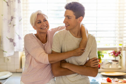 Mom hugging her teenaged son in their kitchen.